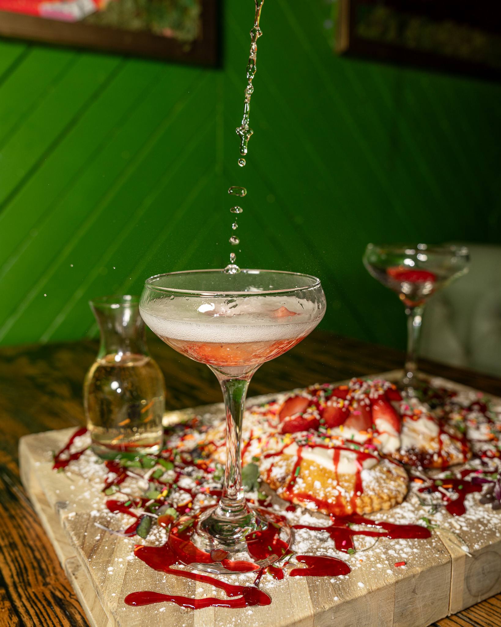 Champagne being poured over a board of strawberry pop-tarts at brunch.