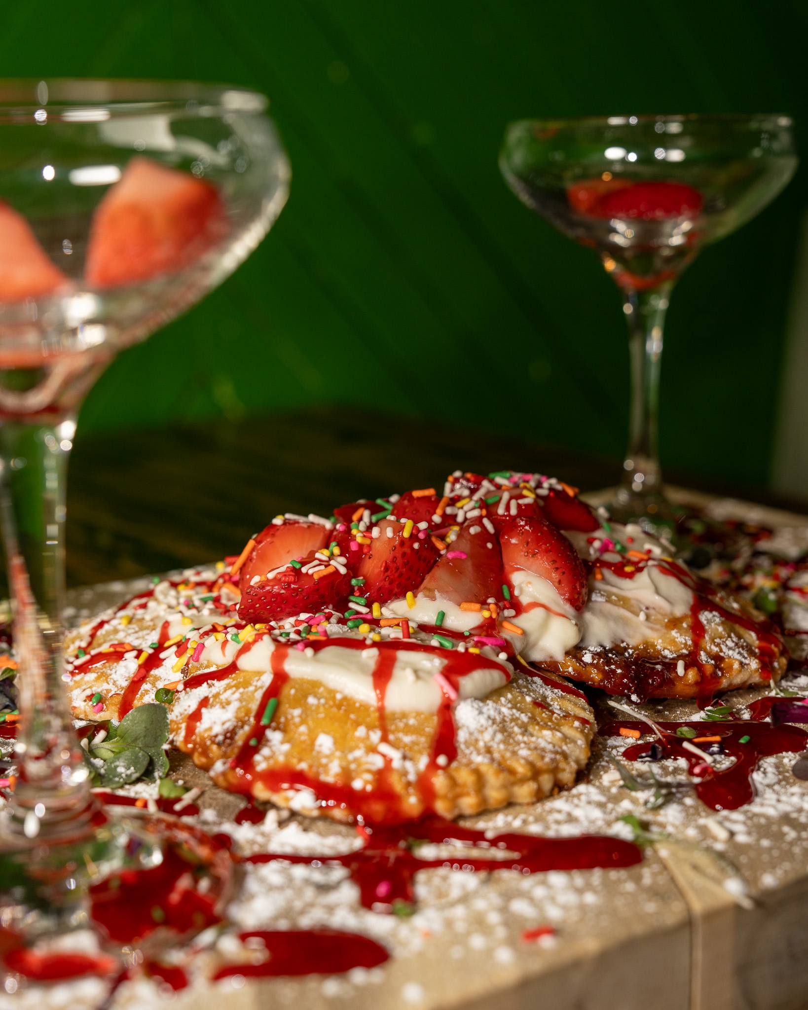 Close-up of house-made strawberry pop-tarts with pink icing, topped with fresh strawberries.