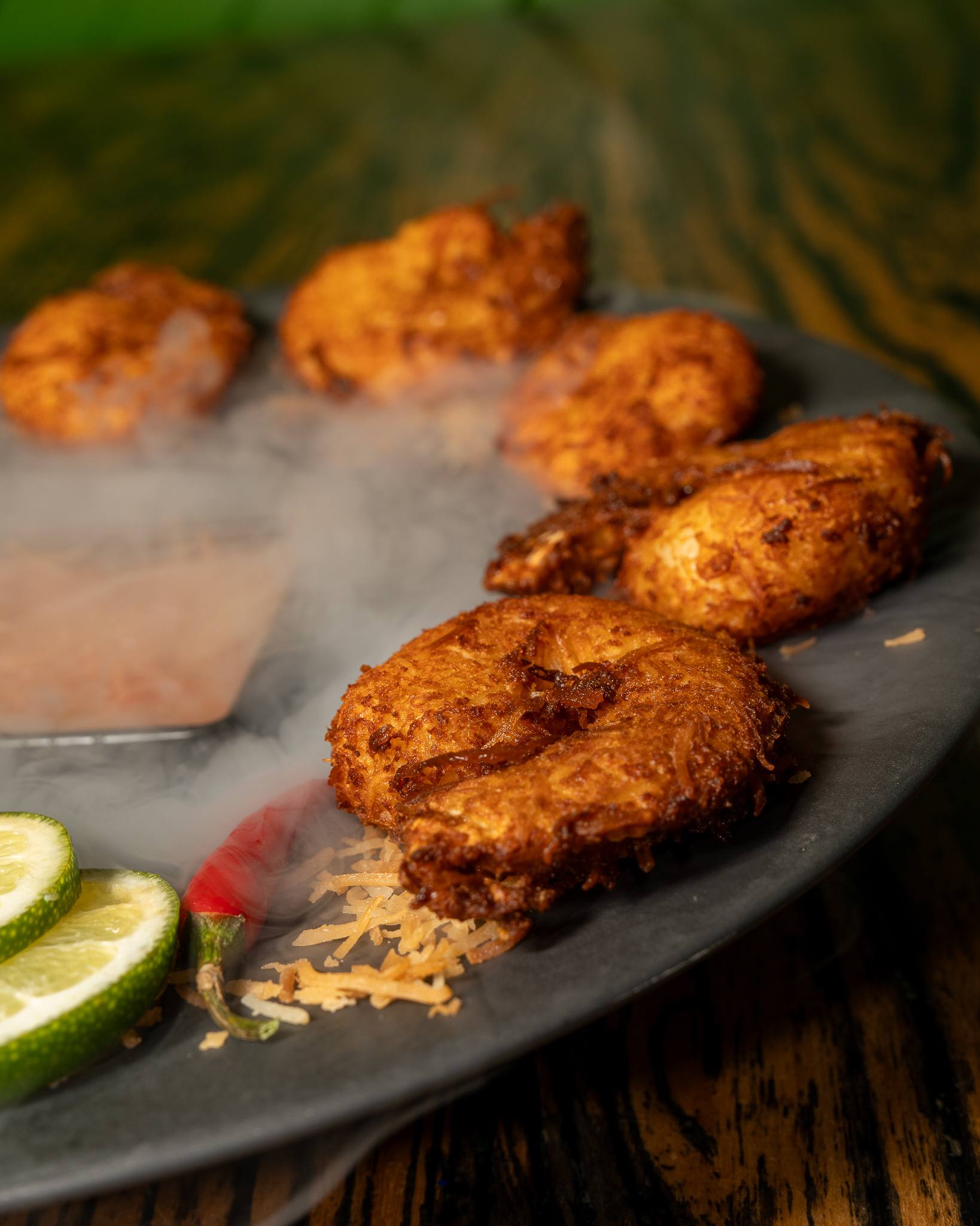 Coconut-crusted shrimp on a dark plate with smoke curling off the dish.