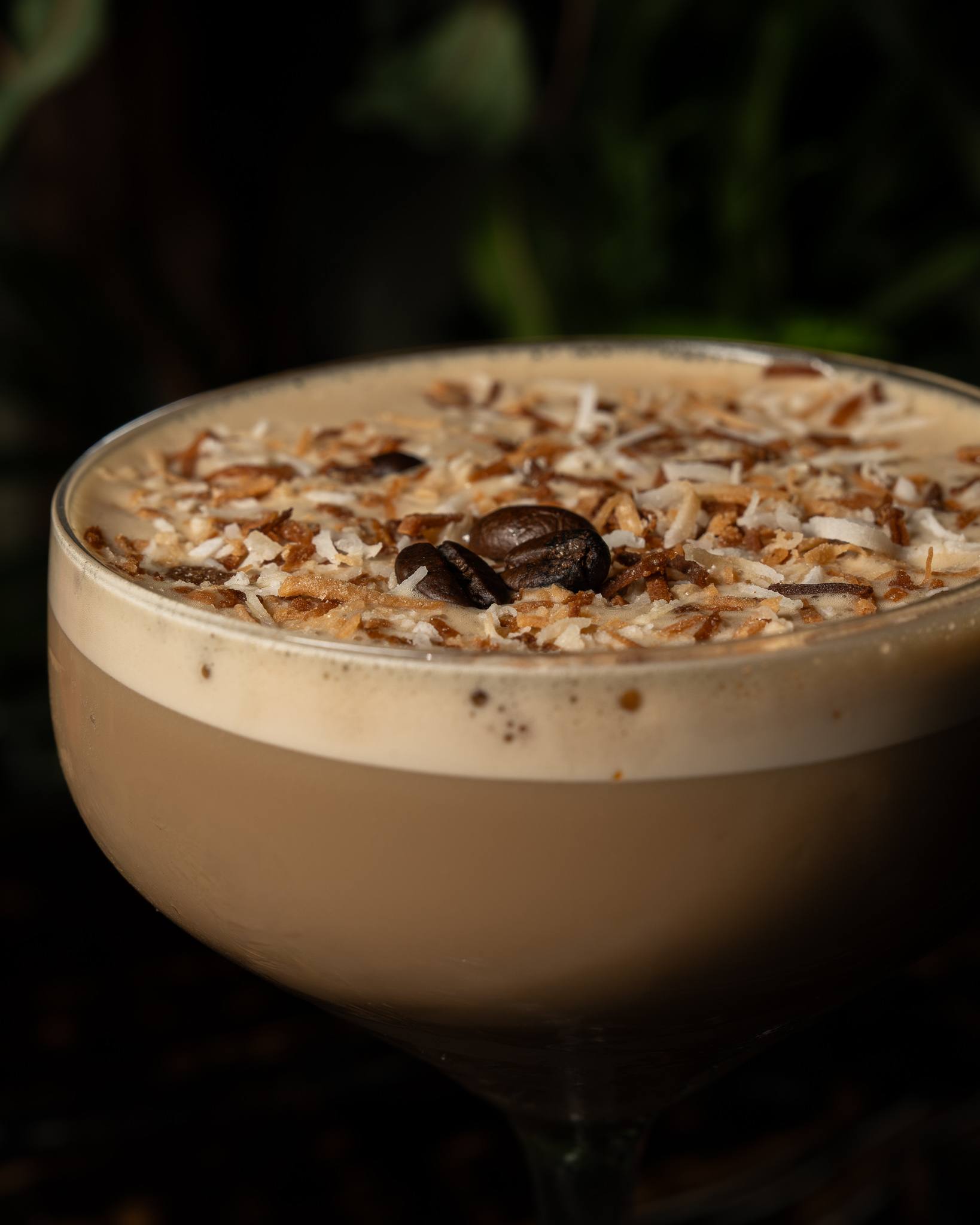 Close-up of toasted coconut and coffee beans on the foam of an espresso martini.